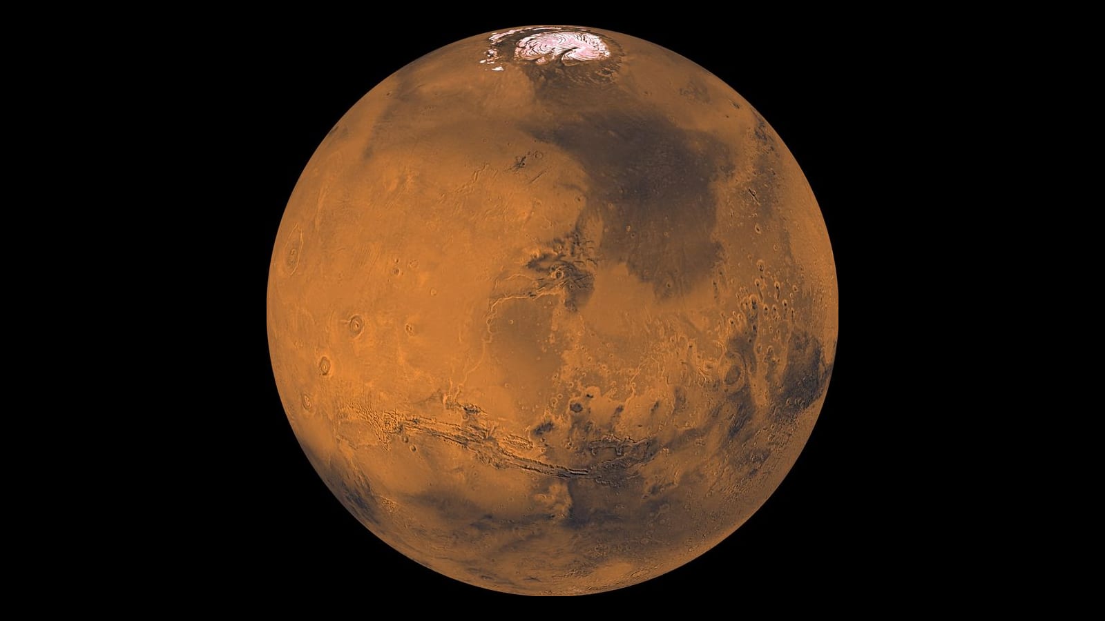 Mars seen whole, with its white northern polar cap at the top and the Valles Marineris canyons across the middle